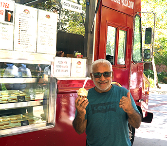 Staff member Ricky Ruiz with his ice cream next to ice cream truck